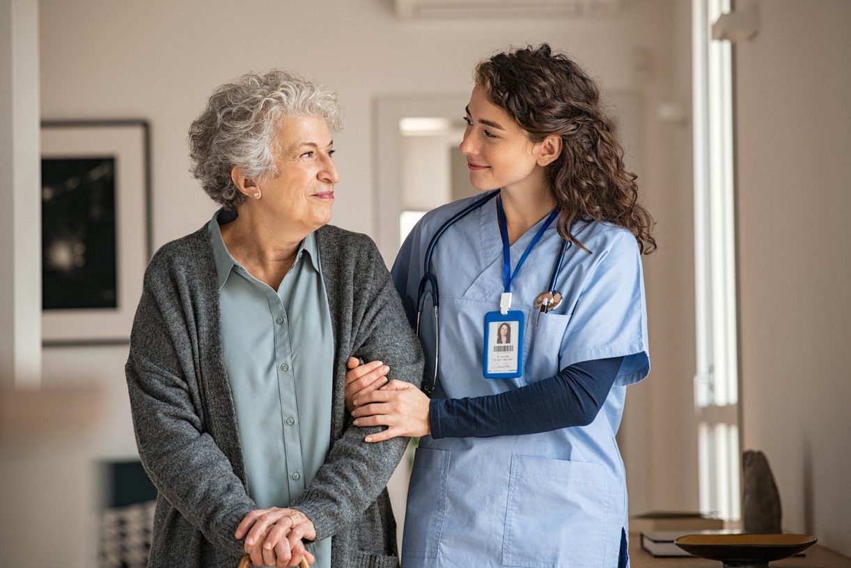 A nurse supporting a senior woman at home